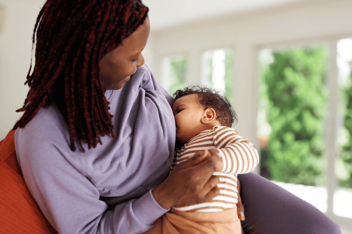 אמא יושבת בסלון ומניקה את התינוקת שלה 