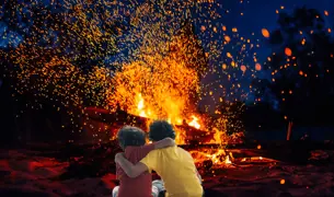 שני ילדים מחובקים ליד מדורה גדולה בלג בעומר