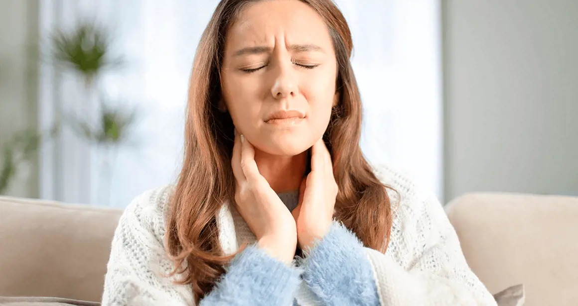 A woman touches her throat