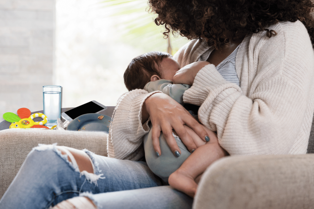 אמא יושבת בסלון ומניקה את התינוקת הקטנה שלה 