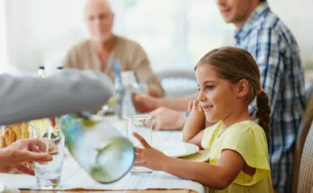 משפחה מסביב לשולחן, ילדה מחכה למים מאימא