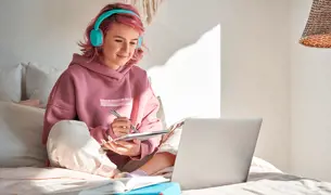 אישה צעירה לומדת מול מחשב עם אוזניות תכלת