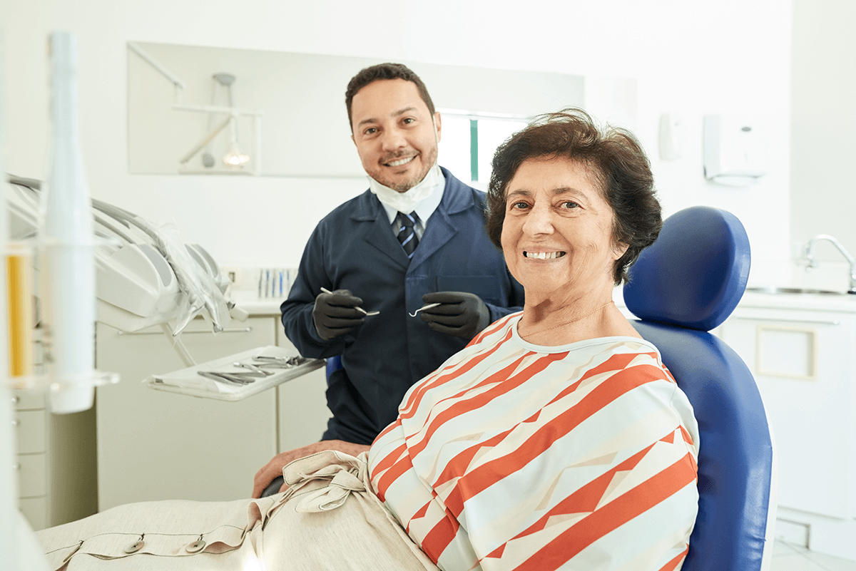 אישה מבוגרת מחייכת אצל רופא שיניים של לאומית 