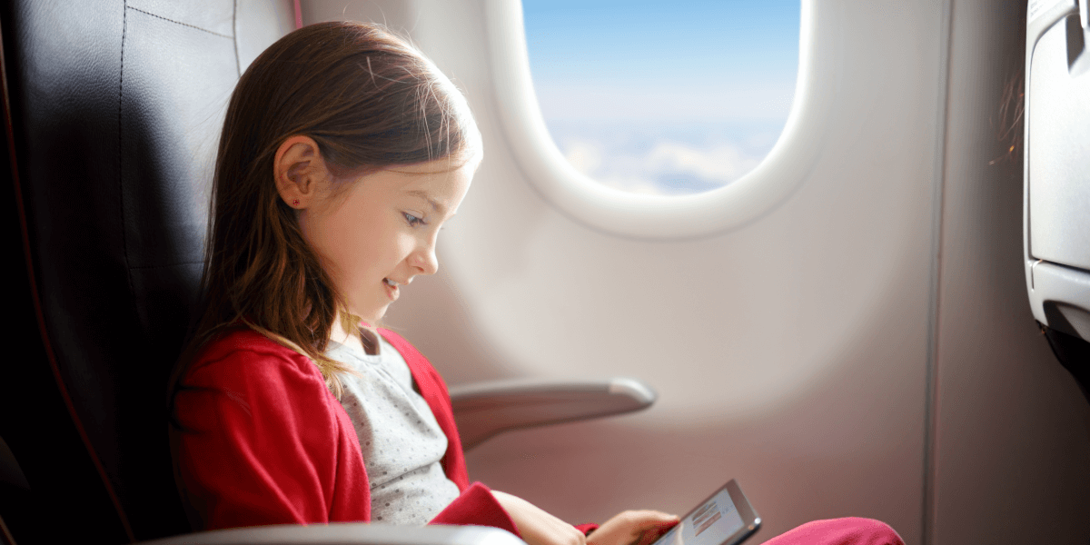 ילדה יושבת ליד חלון המטוס, לטיסה רגועה בזכות ביטוח הנסיעות של לאומית 