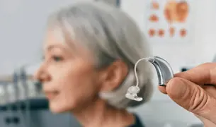 אישה כבת 50 מתנסה עם מכשירי שמיעה חדשים