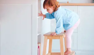 תינוקת מטפסת על כיסא במטבח