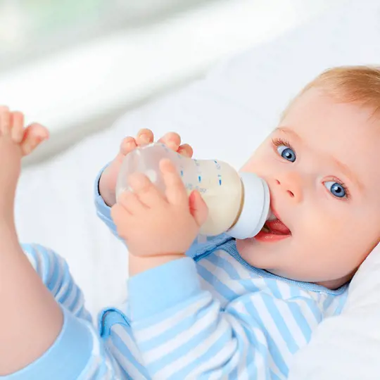 A baby drinks a bottle of milk