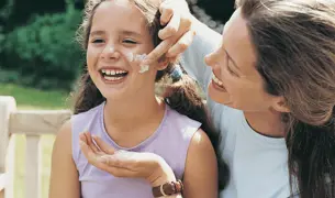 אמא מורחת קרם הגנה על הילדה שלה