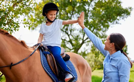 A girl rides a horse with a midwife