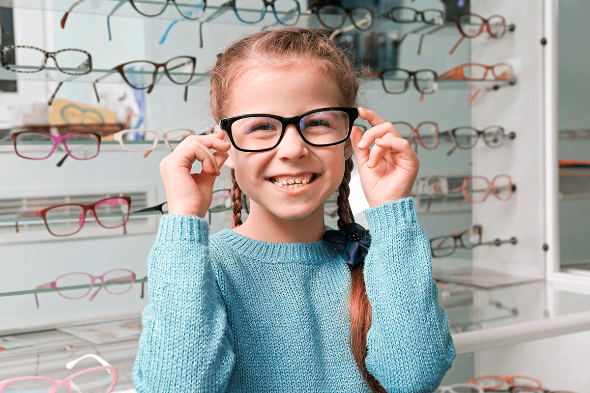 ילדה קטנה מודדת ומתנסה בזוגות של משקפיים באחת מחנויות האופרטיקה שבהסדר עם לאומית