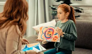 טיפול באומנות התפתחות הילד ילדה מראה למטפלת את הציור שציירה