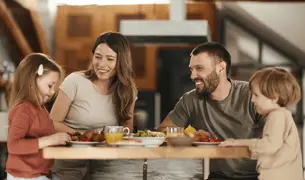 אימא ואבא ילד וילדה יושבים מסביב לשולחן לארוחה משפחתית