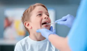 רופא בודק את הגרון של הילד בעזרת מקל עץ