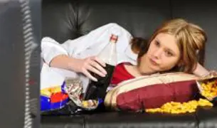 נערה עושה בינג אוכל מול הטלוויזיה