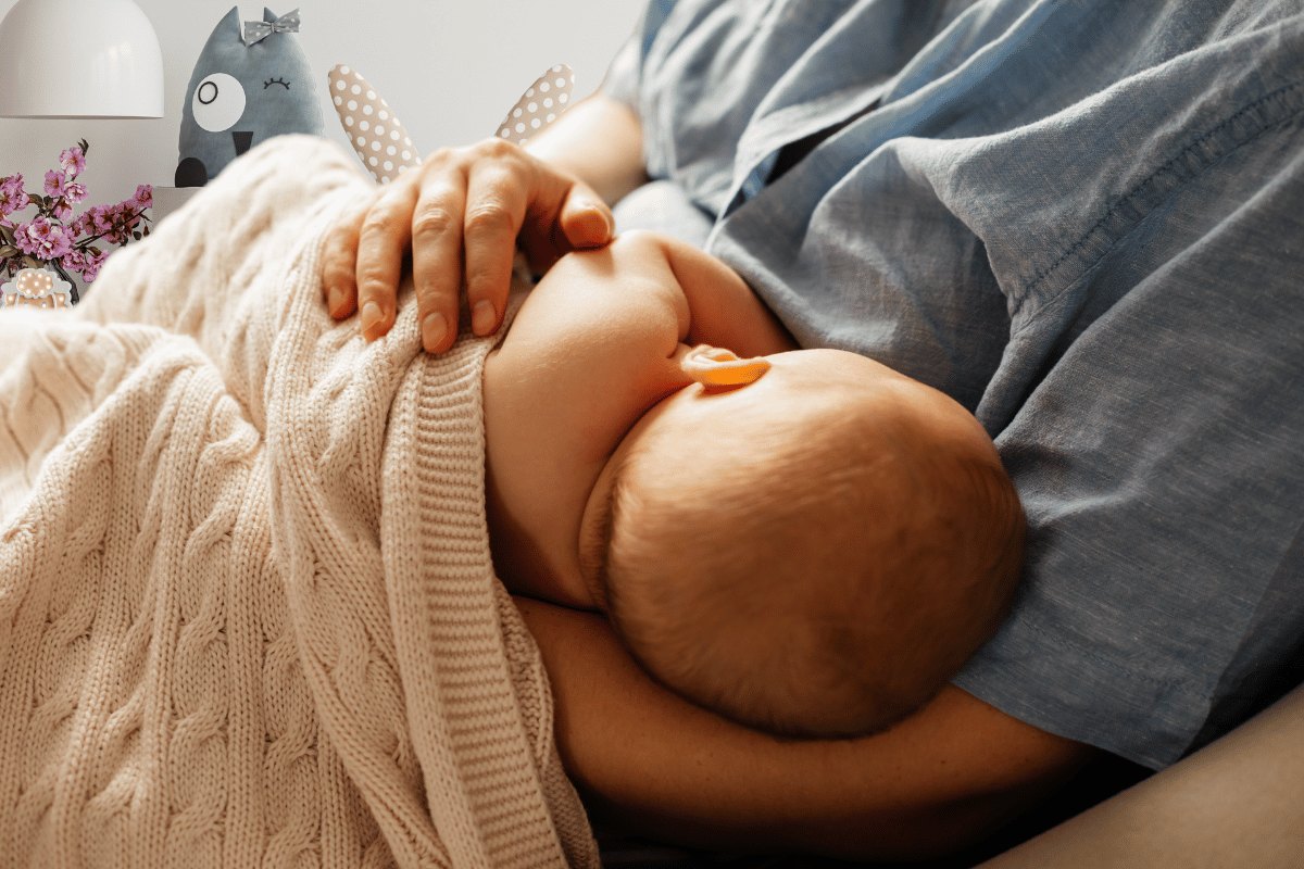 אמא יושבת בחדר הילדים ומניקה את התינוק שלה