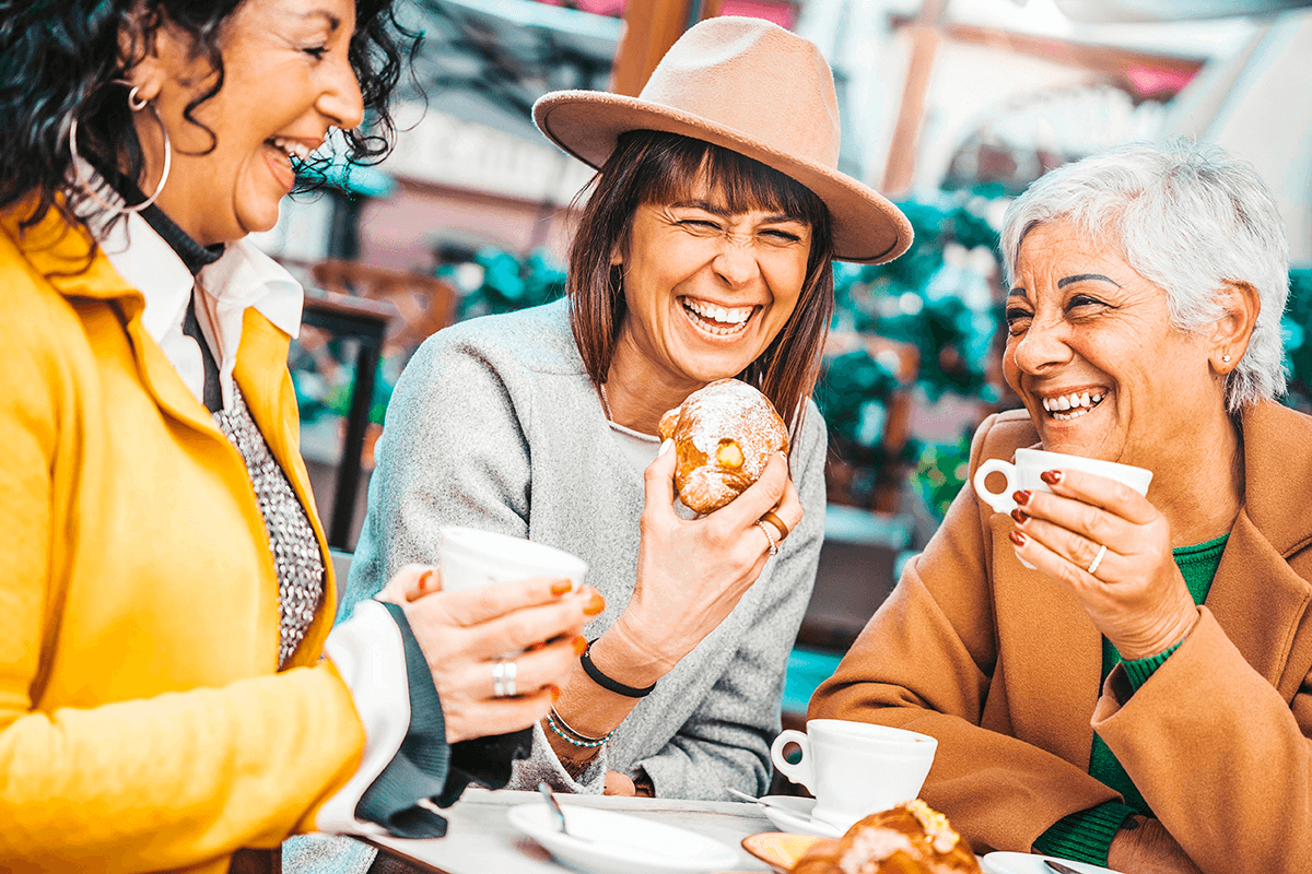 קבוצת נשים בגיל המעבר שותות קפה וצוחקות יחד