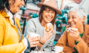קבוצת נשים בגיל המעבר שותות קפה וצוחקות יחד