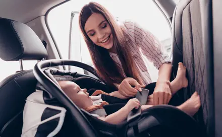 Mother belts the baby in a booster seat
