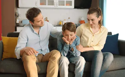 אבא ואימא מחבקים את ילדם