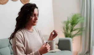 אישה מטפטפת טיפות לתוך כוס