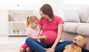 אמא הריונית משחקת על הרצפה עם הבת הקטנה שלה