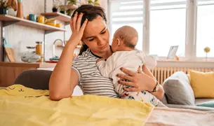 אמא חדשה מחזיקה תינוק קטן מאד עייפה