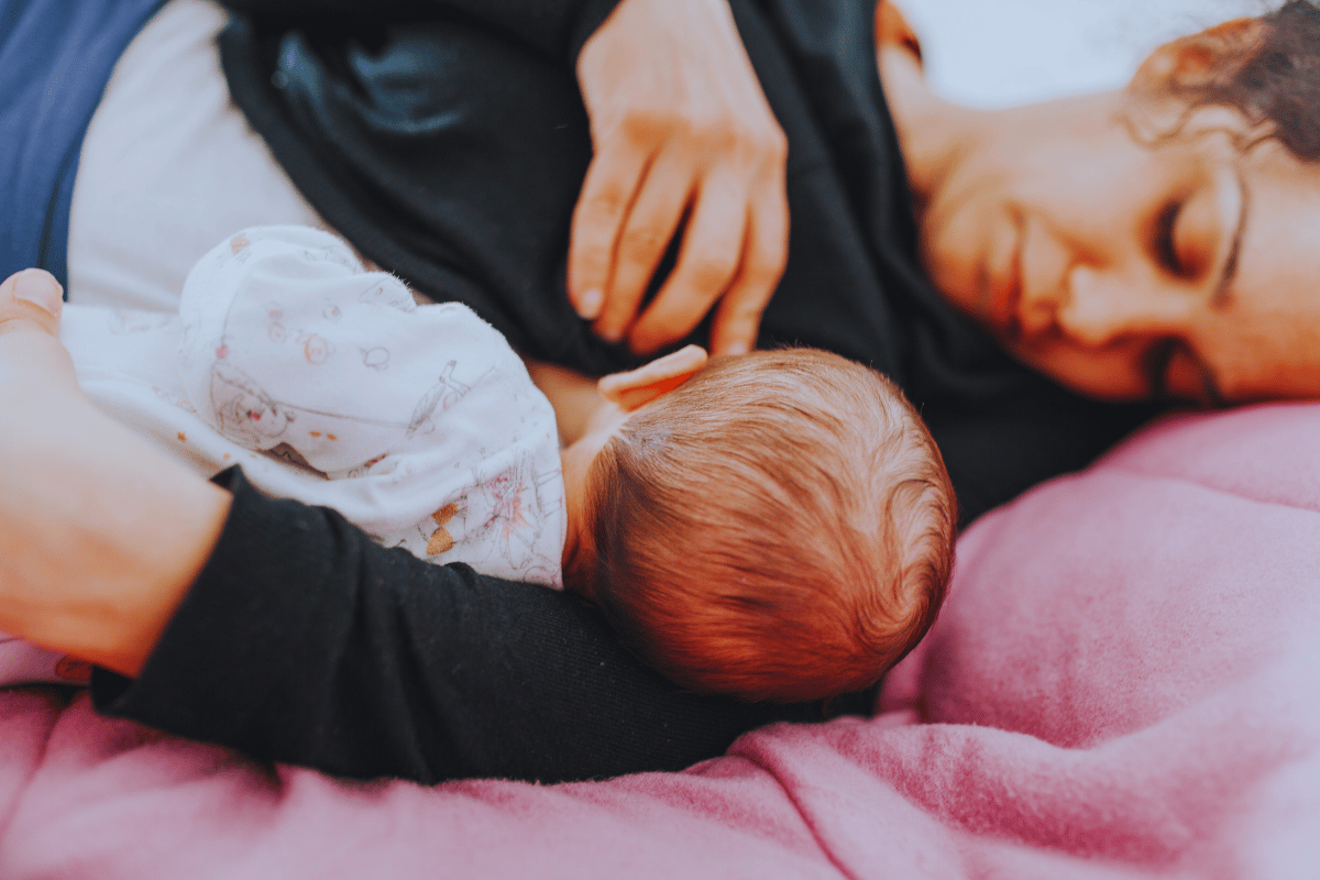 אמא שוכבת על המיטה ומניקה בשכיבה את התינוק