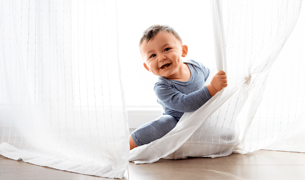 תינוק בן שנה משחק קוקו מאחורי וילון