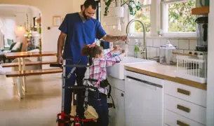 ילדה עם הליכון והמטפל שלה יחד שוטפים ידיים 