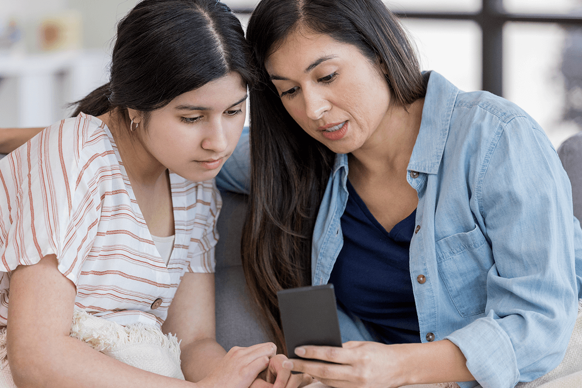אמא מראה לבת המתבגרת שלה משהו בטלפון