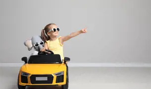 ילדה קטנה נוהגת ברכב צעצוע הצהוב שלה