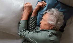 אישה מבוגרת מנסה לישון במיטה