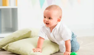 תינוקת בת 9 חודשים זוחלת עם רעשן ביד