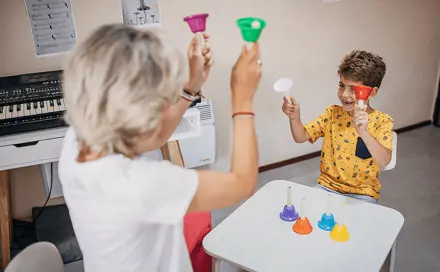 אישה מבוגרת עם ילד, שניהם מחזיקים פעמונים