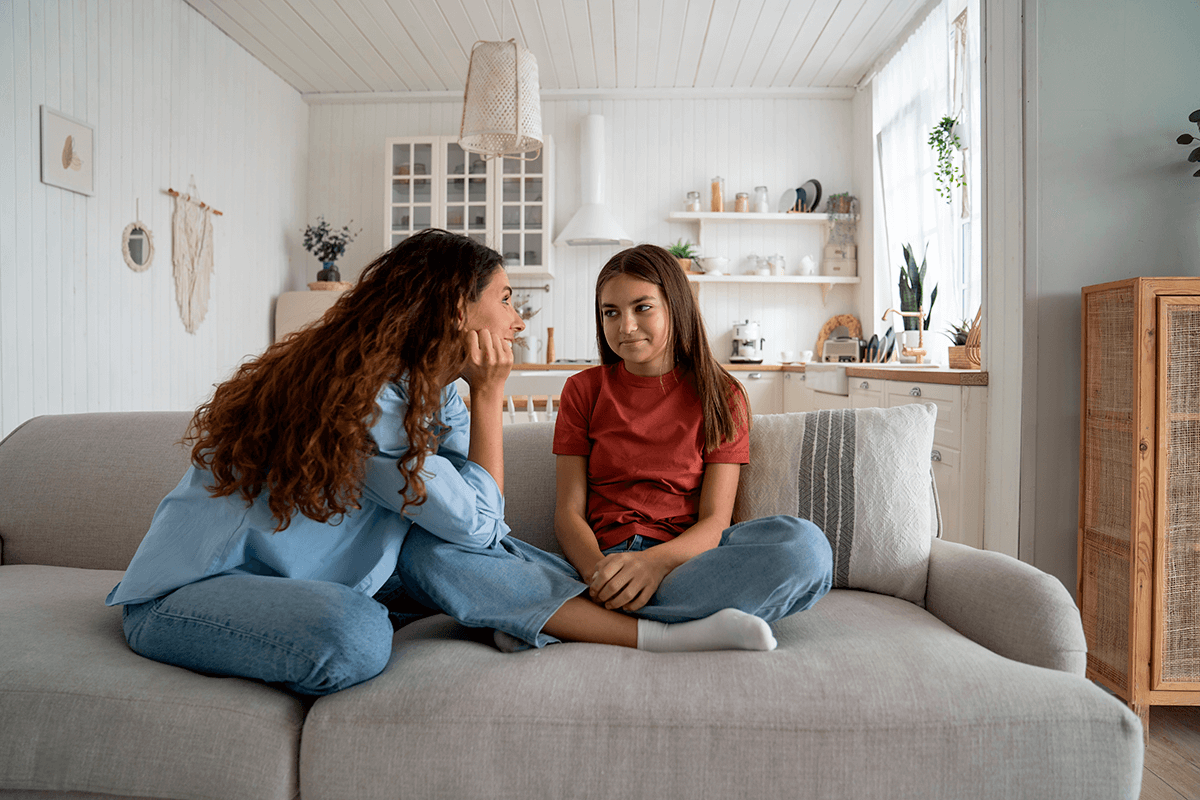 אמא וילדה יושבות יחד עם הספה ומדברות