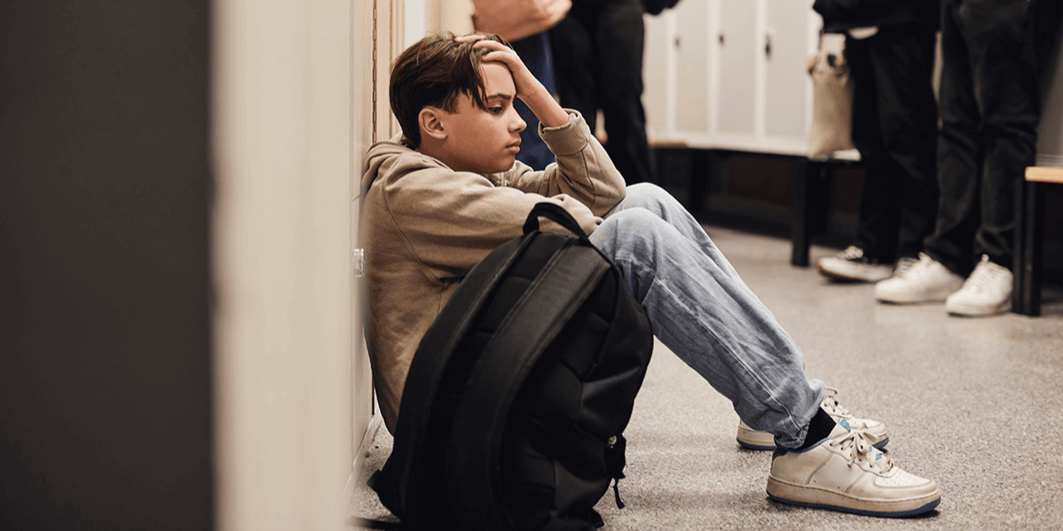 נער מדוכא יושב לבד במסדרון בית הספר