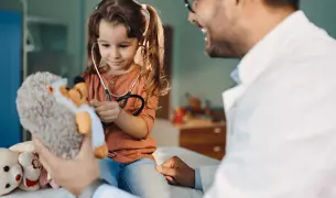 רופא ילדים משחק עם ילדה קטנה