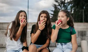 שלושה נערות אוכלות תפוח